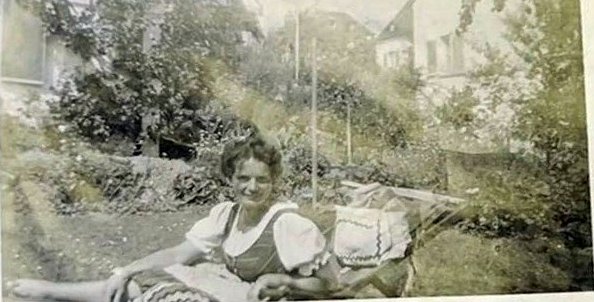 Junge Frau im Dirndl liegt im Garten