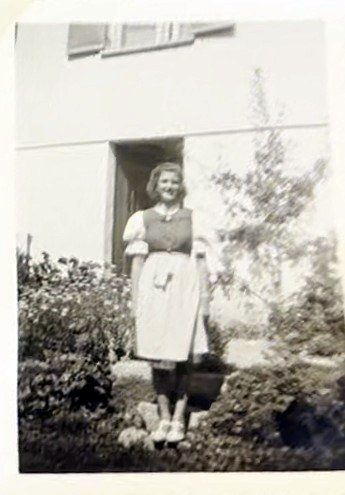 Junges Mädchen im Dirndl vor dem Haus