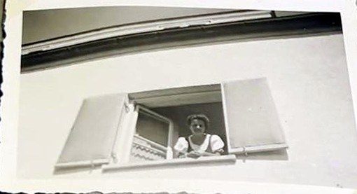 Frau schaut aus einem Fenster mit Läden
