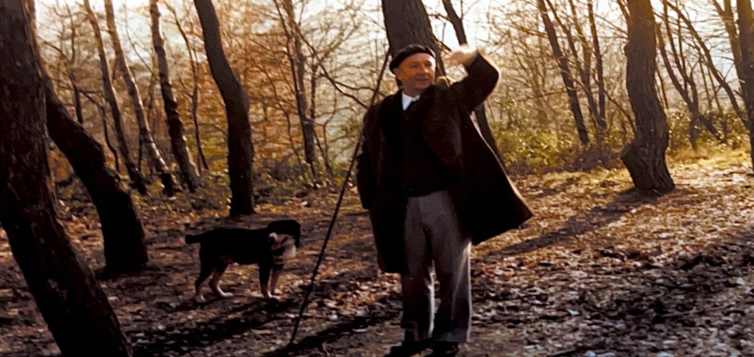 Mann mit Hund im herbstlichen Wald